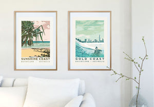 Sunshine Coast poster 'Pandanus' and Gold Coast poster 'Blue Surfer' in wooden frames hanging on a white wall above a white sofa